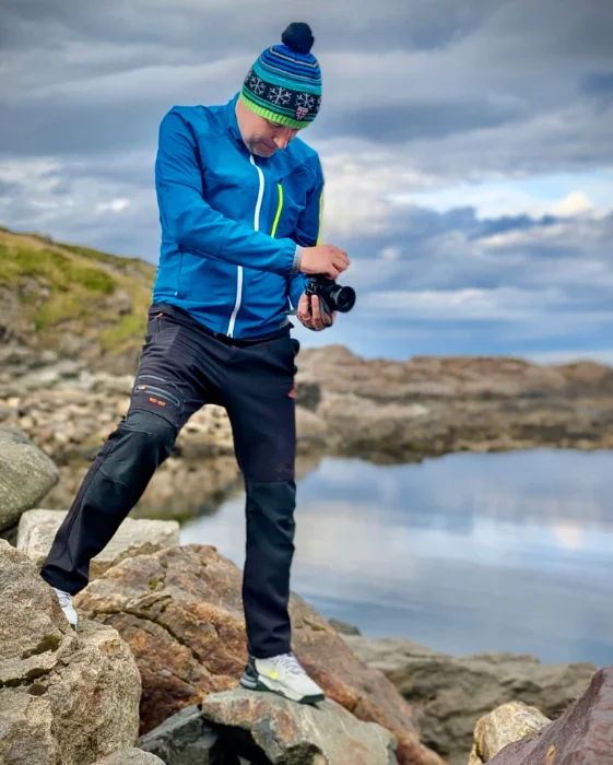 Trainer René Rockott beim Fotografieren an der felsigen Küste